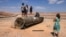 People stand on top of the remains of an Iranian missile in the Negev desert near Arad, on October 2, 2024, in the aftermath of an Iranian missile attack on Israel.