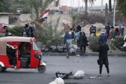 Young men charge into a struggle between protesters and riot police carrying homemade shields reading slogans like, "Attention, martyrs are advancing," Jan. 24, 2020, in Baghdad. (Heather Murdock/VOA)