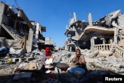 Wapalestina wakioka mikate katika eneo la kifusi cha nyumba zao zilizoharibiwa na mashambulizi ya Israeli wakati wa vita hivyo wakati wa sitisho la mapigano la muda kati ya Hamas and Israel, huko Khan Younis. REUTERS/Mohammed Salem