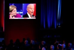 FILE - Guests watch Democratic presidential candidates Sen. Elizabeth Warren, D-Mass., and former Vice President Joe Biden speak on a big screen during a Democratic presidential primary debate in Las Vegas, Feb. 19, 2020.