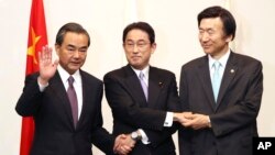 Japanese Foreign Minister Fumio Kishida, center, Chinese Foreign Minister Wang Yi, left, and South Korean Foreign Minister Yun Byung-se, right, pose for photographers prior to the official banquet of the trilateral foreign ministers meeting in Tokyo, Aug.