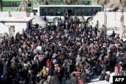 Syrian civilians, evacuated from rebel-held areas in the Eastern Ghouta, gather at a school in the regime-controlled Hosh Nasri, on the northeastern outskirts of the capital Damascus.
