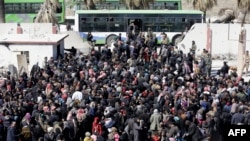 Warga sipil Suriah yang dievakuasi dari daerah yang dikuasai pemberontak di Ghouta Timur, berkumpul di sebuah sekolah di Hosh Nasri yang dikendalikan rezim tersebut, di pinggiran timur laut ibukota Damaskus pada 16 Maret 2018, sebelum dipindahkan ke daerah lain.