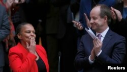 Outgoing French Justice Minister Christiane Taubira (L) reacts to her staff members near newly-appointed French Justice Minister Jean-Jacques Urvoas (R) during a handover ceremony at the Justice Ministry in Paris, Jan. 27, 2016. 