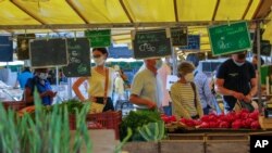 People wearing protective face masks as a precaution against the conoravirus shop at a outdoor market in Versailles, west of Paris, Sept. 11, 2020.