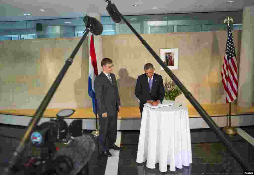 U.S. President Barack Obama signs the book of condolence for the Malaysia Airlines Flight MH17 disaster at the Embassy of the Netherlands, as Deputy Chief of Mission Peter Mollema watches, Washington, July 22, 2014.