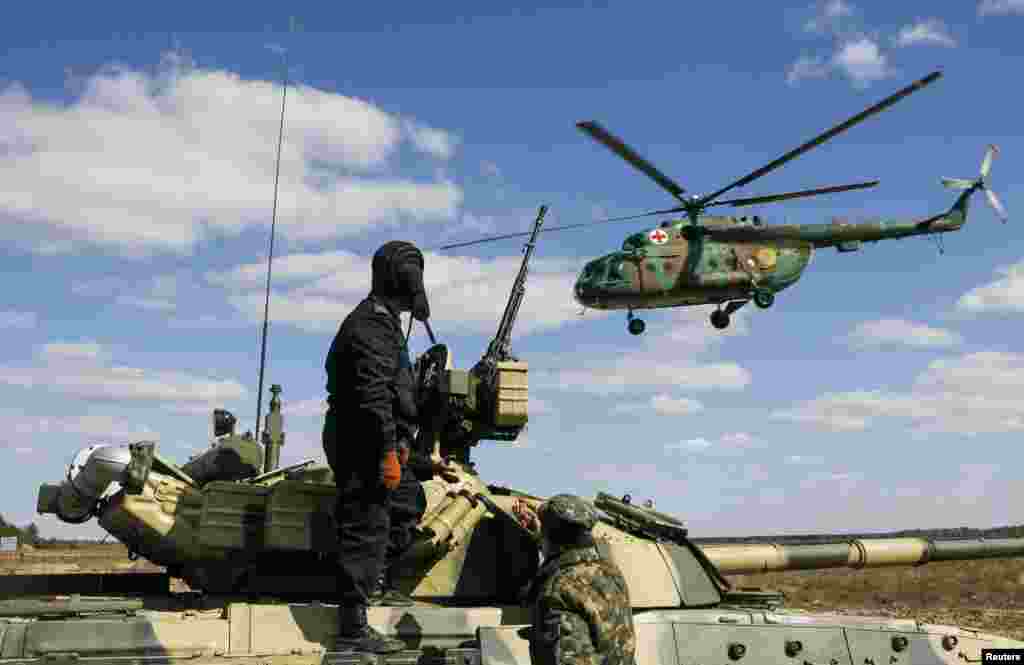 Ukrainian soldiers watch as an army medic helicopter flies above during a military exhibition near the settlement of Desna in Chernigov region, April 2, 2014. 