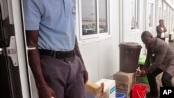 Le vice-ministre libérien de la Santé Tolbert Nyenswah, à droite, se lave les mains avant de faire une annonce au bureau de l’Organisation mondiale de la santé à Monrovia, 14 janvier 2016. 