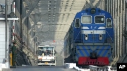 资料照- 一名中国武警卫兵注视着经朝中边境的友谊桥从朝鲜一方驶入中国丹东市的客运火车和大巴。
