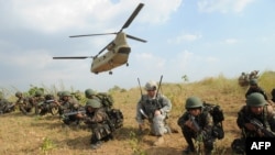 FILE - Philippine soldiers and a U.S. Army soldier from 2nd Stryker Brigade Combat of the 5th Infantry Division based in Hawaii take their positions after disembarking from a C-47 Chinook helicopter during an air assault exercise inside the military training camp of Fort Magsaysay in Nueva Ecija province north of Manila, April 20, 2015, at the start of joint U.S.-Philippines annual military exercises. 