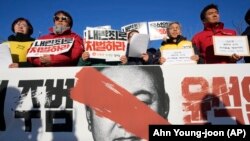 ผู้ประท้วงถือป้ายเรียกร้องปธน.เกาหลีใต้ ยูน ซุก ยอล ให้ลาออก ด้านหน้าสภาในกรุงโซล เกาหลีใต้ 4 ธ.ค. 2024 (AP Photo/Ahn Young-joon)