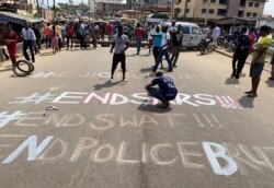 A demonstrator paints 'End Sars', referring to the Special Anti-Robbery Squad police unit, on a street during a protest demanding police reform in Lagos, Nigeria, Oct, 20, 2020.