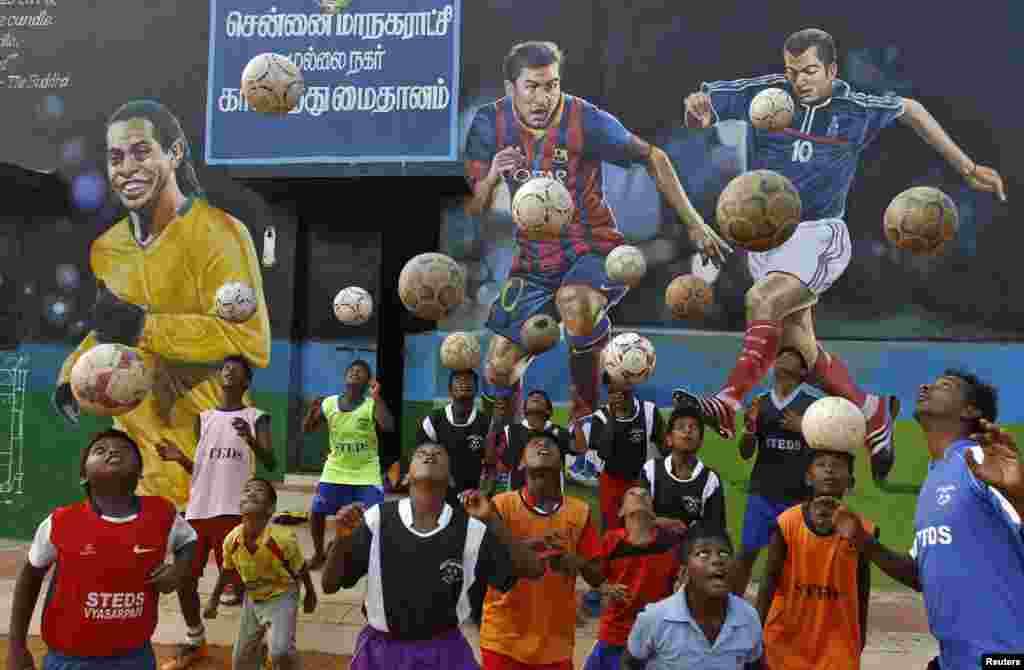 Boys practice during a heading drill in front of murals of (L-R), Brazil&#39;s Ronaldinho, Argentina&#39;s Lionel Messi and France&#39;s Zinedine Zidane, at a playground in the southern Indian city of Chennai.