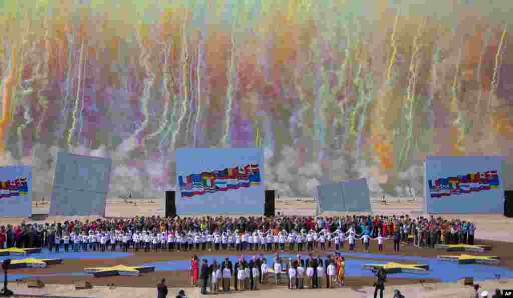 Colored smoke fills the sky as WWII veterans stand to attention flanked by children during an international ceremony marking the 70th anniversary of the Allied landings on D-Day on Sword Beach in Ouistreham, in Normandy, June 6, 2014.