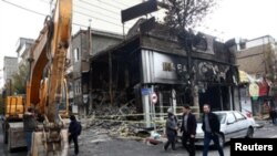 People walk near a burnt bank, after protests against increased fuel prices, in Tehran, Iran November 20, 2019. Picture taken November 20, 2019.