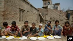 Nepalese children wait for the food to be distributed as they sit next to their houses damaged in a rainstorm in Bara district, 125 kilometers (75 miles) south of Kathmandu, Nepal, April 1, 2019.