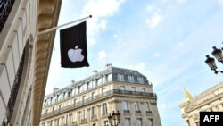 Bendera dengan logo perusahaan Apple terlihat di luar toko Apple di Paris, Prancis (foto: dok). 