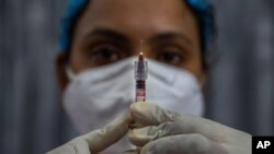 A health worker checks a syringe before performing a trial run of a COVID-19 vaccine delivery system, as India prepares to kick off the coronavirus vaccination drive, in Gauhati, India, Jan. 8, 2021. 