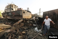 FILE - Workers inspect damage at the site of an airstrike on the maintenance hub at the Hodeidah port, Yemen, May 27, 2018.