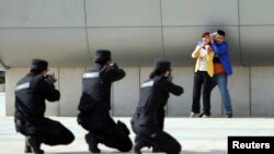 2014年五月7日，中国郑州警方在火车站举行反恐演习。武装警察举枪瞄准一个劫持妇女的恐怖分子的扮演者