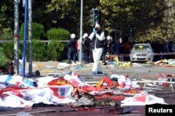 A police forensic expert takes pictures as he examines the scene following explosions during a peace march in Ankara, Turkey, Oct. 10, 2015.