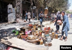 FILE - Afghan shopkeepers try to recover items from burning shops after a Taliban attack in Ghazni city, Afghanistan, Aug. 14, 2018.