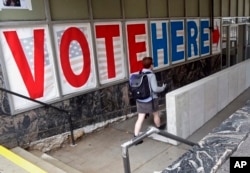 FILE - A voter passes a large sign before voting in Minneapolis.