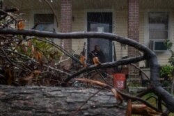 A local resident is framed by debris from Hurricane Laura, as he watches the arrival of Hurricane Delta from his doorsteps in Lake Charles, Louisiana, Oct. 9, 2020.