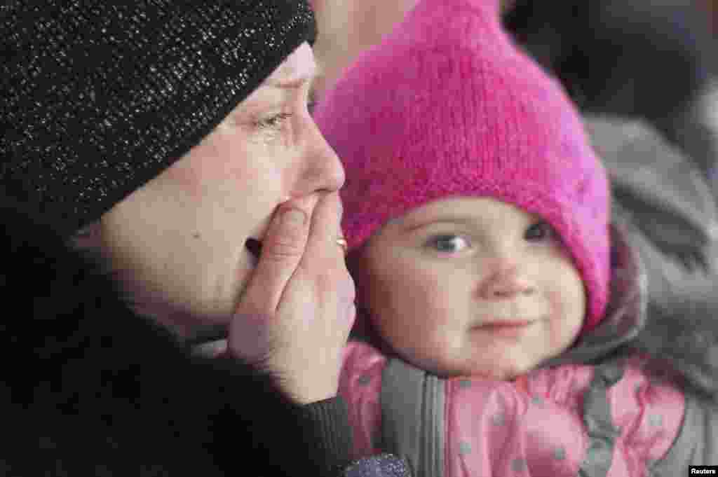 A woman cries as she holds a child while on a bus waiting to flee the military conflict in Debaltseve, Feb. 3, 2015.