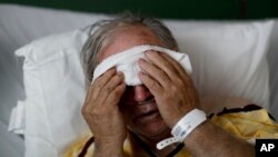 FILE - A flu patient places a cold compress on his forehead at Upson Regional Medical Center in Thomaston, Ga., Feb. 9, 2018.