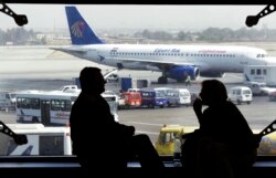 FILE - Tourists wait for their flight, as an Egyptair plane is seen, background, at a waiting hall in Cairo's international airport in Egypt.