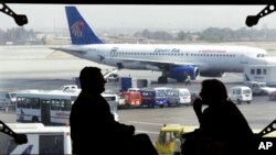 FILE - Tourists wait for their flight, as an Egyptair plane is seen, background, at a waiting hall in Cairo's international airport in Egypt. 
