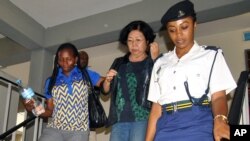 នៅ​ក្នុង​រូបភាព​ដែល​ថត​កាលពី​ថ្ងៃទី៧ ខែតុលា ឆ្នាំ២០១៥ ស្ត្រី​ជំនួញ​ជនជាតិ​ចិន​ម្នាក់​ឈ្មោះ Young Feng Glan (រូប​កណ្តាល) ត្រូវ​អម​ដោយ​ប៉ូលិស​ចេញ​ពី​តុលាការ​នៅ​ក្នុង​ក្រុង Dar es Salaam ប្រតេស​តង់សានី។