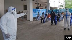 បុគ្គលិក​ម្នាក់​នៃ​សាកលវិទ្យាល័យ​វេជ្ជសាស្ត្រ​ Mugda និង​មន្ទីរពេទ្យ បាន​ធ្វើ​​កាយវិទការ ខណៈ​ដែល​លោក​ណែនាំ​ដល់​ពលរដ្ឋ​​ដែល​រង់ចាំ​ធ្វើ​តេស្ត​រក​ជំងឺ​កូវីដ១៩​ឲ្យ​មក​ធ្វើ​តេស្ត ទីក្រុង​ដាកា ប្រទេស​បង់ក្លាដែស ថ្ងៃ​ទី​១៧ ខែមិថុនា ឆ្នាំ​២០២០។ 