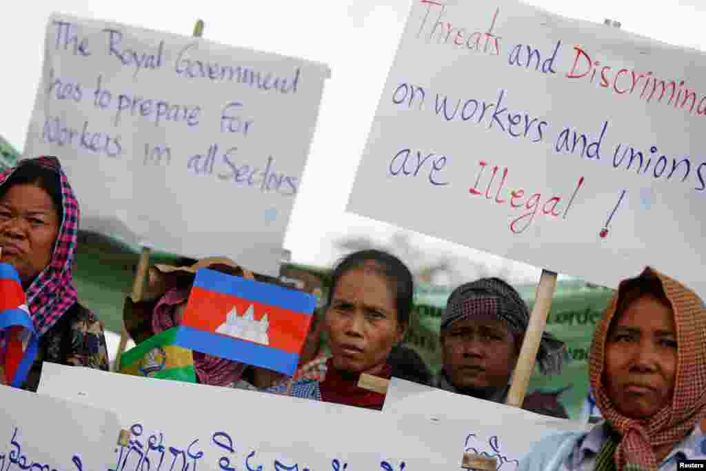 Workers hold flags and signs as they rally to mark May Day in Phnom Penh, Cambodia, May 1, 2018.