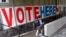 FILE - A voter passes a large sign before voting in Minneapolis.