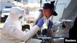 Seorang petugas melakukan tes Covid-19 di Pusat Layanan Hochfelln di dekat kota Bergen, Jerman, 30 July 2020. (REUTERS/Michael Dalder). 