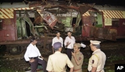FILE - Police investigate near a train destroyed by a bomb blast at Mahim railway station in Mumbai, India, July 11, 2006.