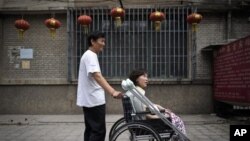 Pada foto yang diambil tanggal 30 Juni 2010 ini, Ni Yulan (duduk di kursi roda) dibantu Don Jiqin, suaminya, menikmati udara sore Beijing (Foto: dok).