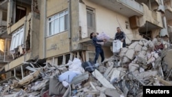 Arsin dan ayahnya mengeluarkan barang-barang dari apartemen mereka yang hancur setelah gempa mematikan di Antakya, Provinsi Hatay, Turki, 20 Februari 2023. (Foto: REUTERS/Eloisa Lopezh)