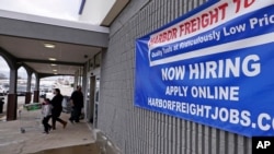 FILE - A 'Now Hiring' sign hangs on the front wall of a Harbor Freight Tools store in Manchester, N.H., Dec. 10, 2020.