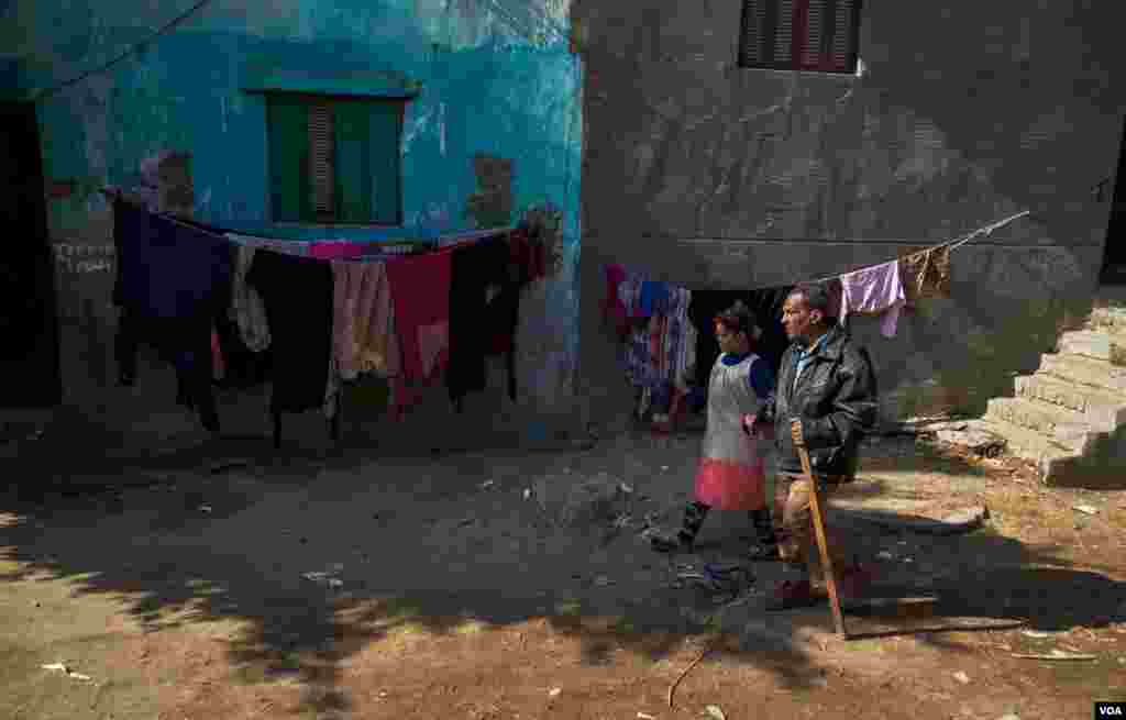 His neighbors help to guide him walking whenever they can. (Hamada Elrasam/VOA)