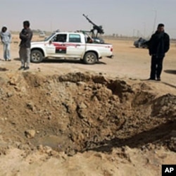 Libyan rebels inspect a crater caused by a bomb dropped by a plane in Ajdabiya on Mar 14 2011 as Libyan strongman Moamer Kadhafi's forces shelled rebel positions