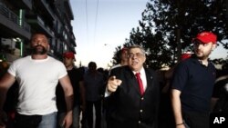 Bersama para pendukungnya, Nikolaos Michaloliakos, Ketua Partai Golden Dawn, berjalan penuh kemenangan melewati jalan-jalan di Athena (photo, 6/5/2012).