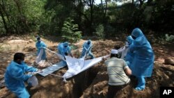 Volunteers and workers bury the body of a COVID-19 victim in Chennai, India, June 5, 2021. 