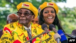 FILE - This file photo taken on November 8, 2017 shows Zimbabwe's President Robert Mugabe (L) addressing party members with Grace Mugabe (R) at his side. (AFP PHOTO / Jekesai NJIKIZANA)