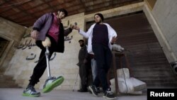 Khamis (R), 24, helps a man with an amputated leg walk using an artificial limb in the rebel-controlled area of Maaret al-Numan town in Idlib province, Syria, March 20, 2016.