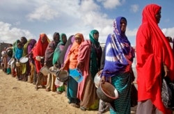 FILE - Newly-arrived women who fled drought queue to receive food distributed by local volunteers at a camp for displaced persons in the Daynile neighborhood on the outskirts of the capital Mogadishu, in Somalia, May 18, 2019.
