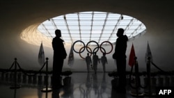 在保安的注视下，北京冬奥会工作人员在奥运塔内为奥林匹克圣火添加燃料。