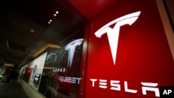FILE - A sign bearing the company logo is seen outside a Tesla store in Cherry Creek Mall in Denver, Colorado, Feb. 9, 2019. 